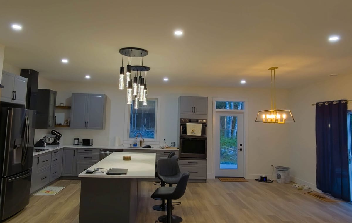 A finished kitchen with pendant lighting over the island and recessed fixtures through the ceiling.
