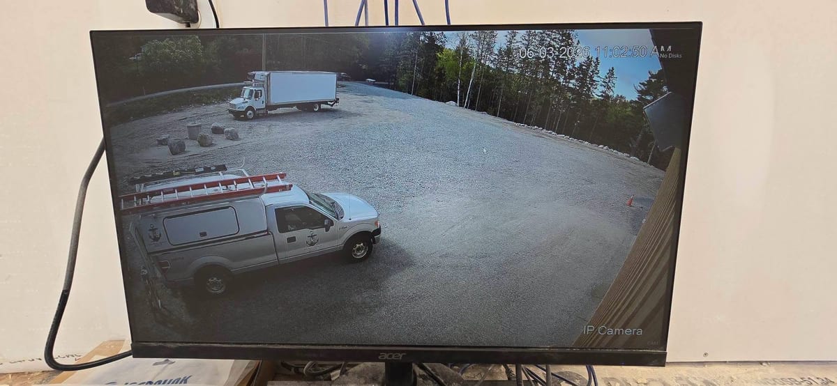 A camera view of a yard and service vehicle on a monitor inside the building.